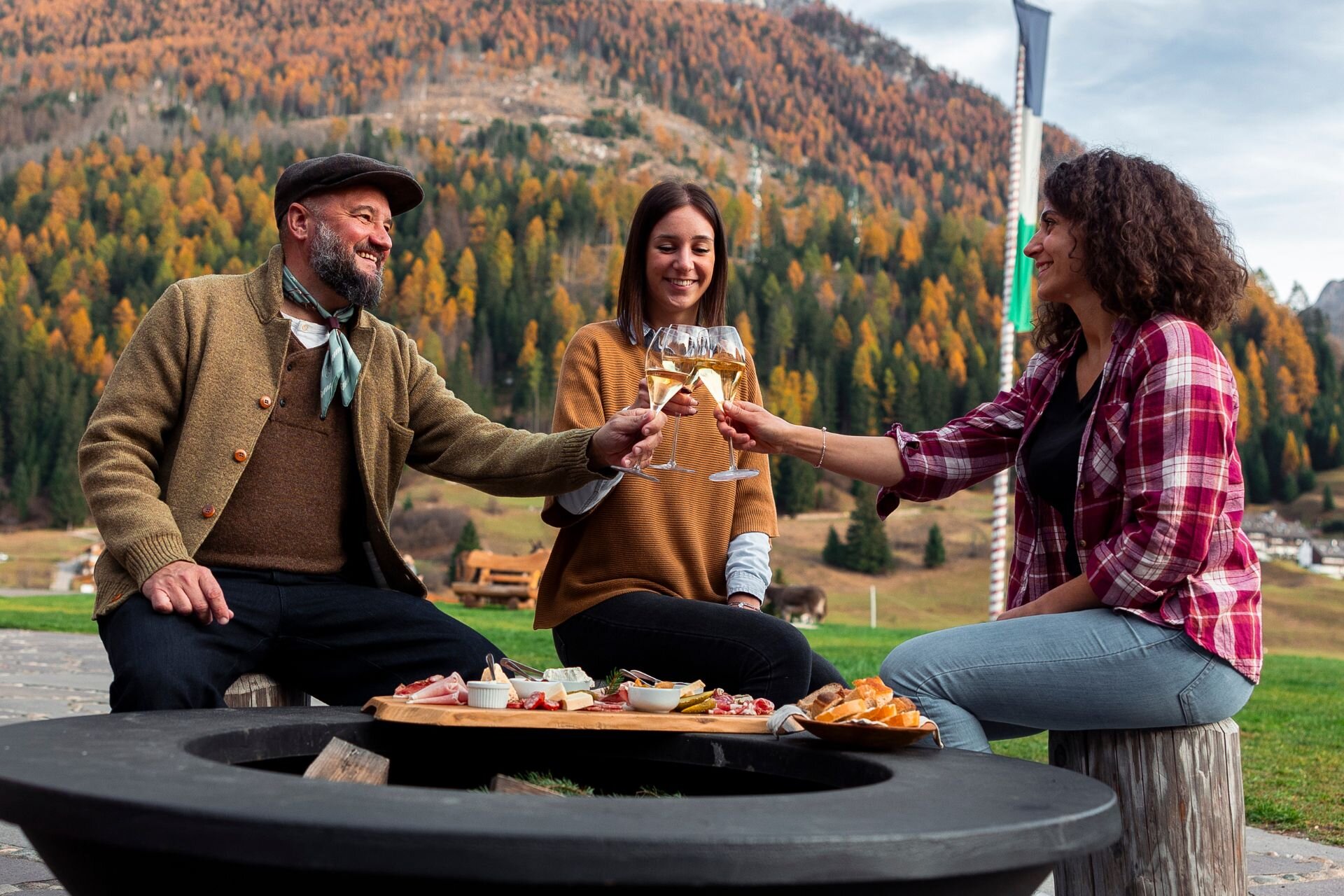 Gruppo di amici brinda davanti ad un tagliere in un agriturismo in val di Fassa in autunno | © Archivio immagini ApT Val di Fassa - Federico Modica