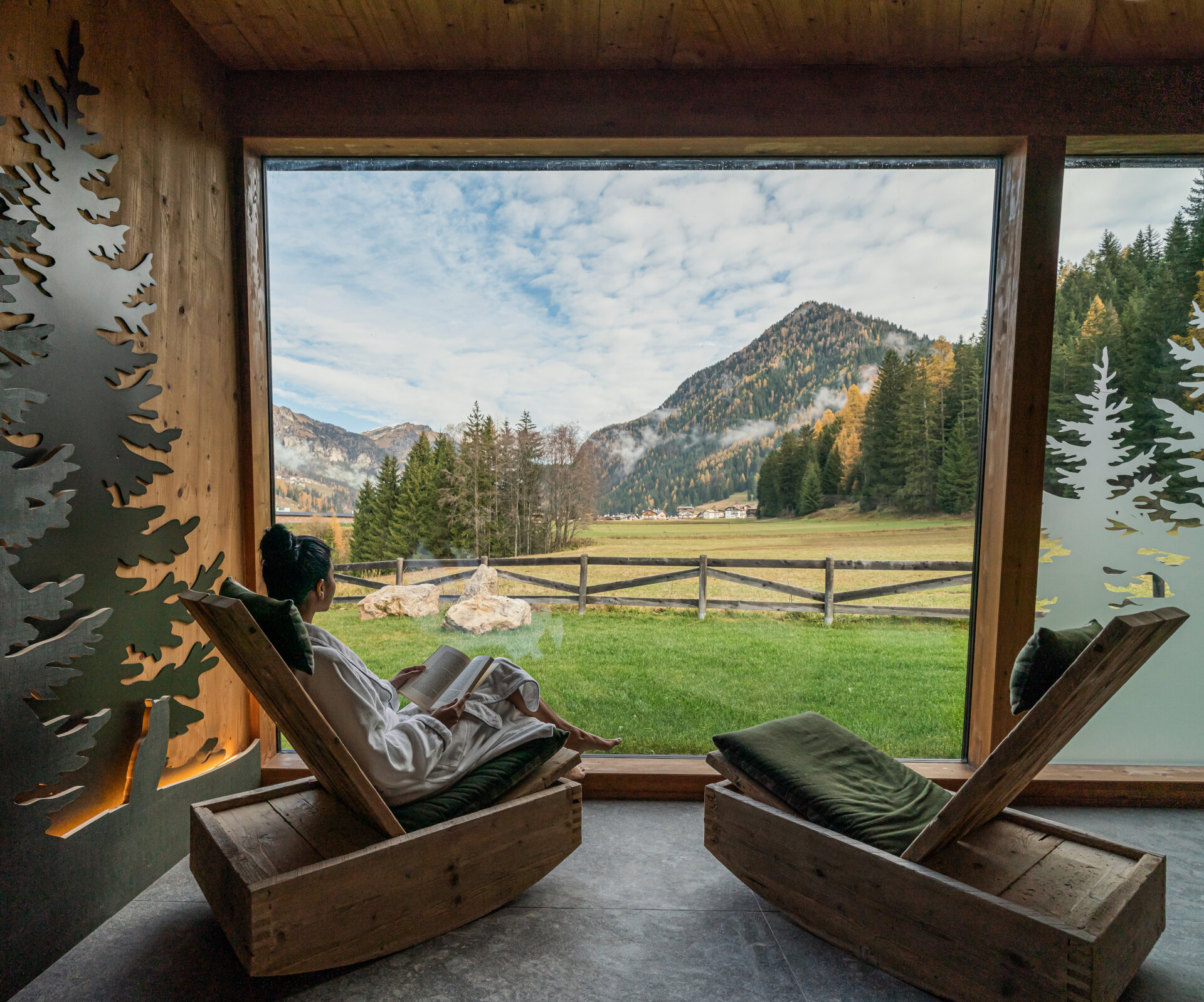 Una donna si rilassa in una sala termale con vista sulle Dolomiti autunnali | © Archivio immagini QCTerme - 2025