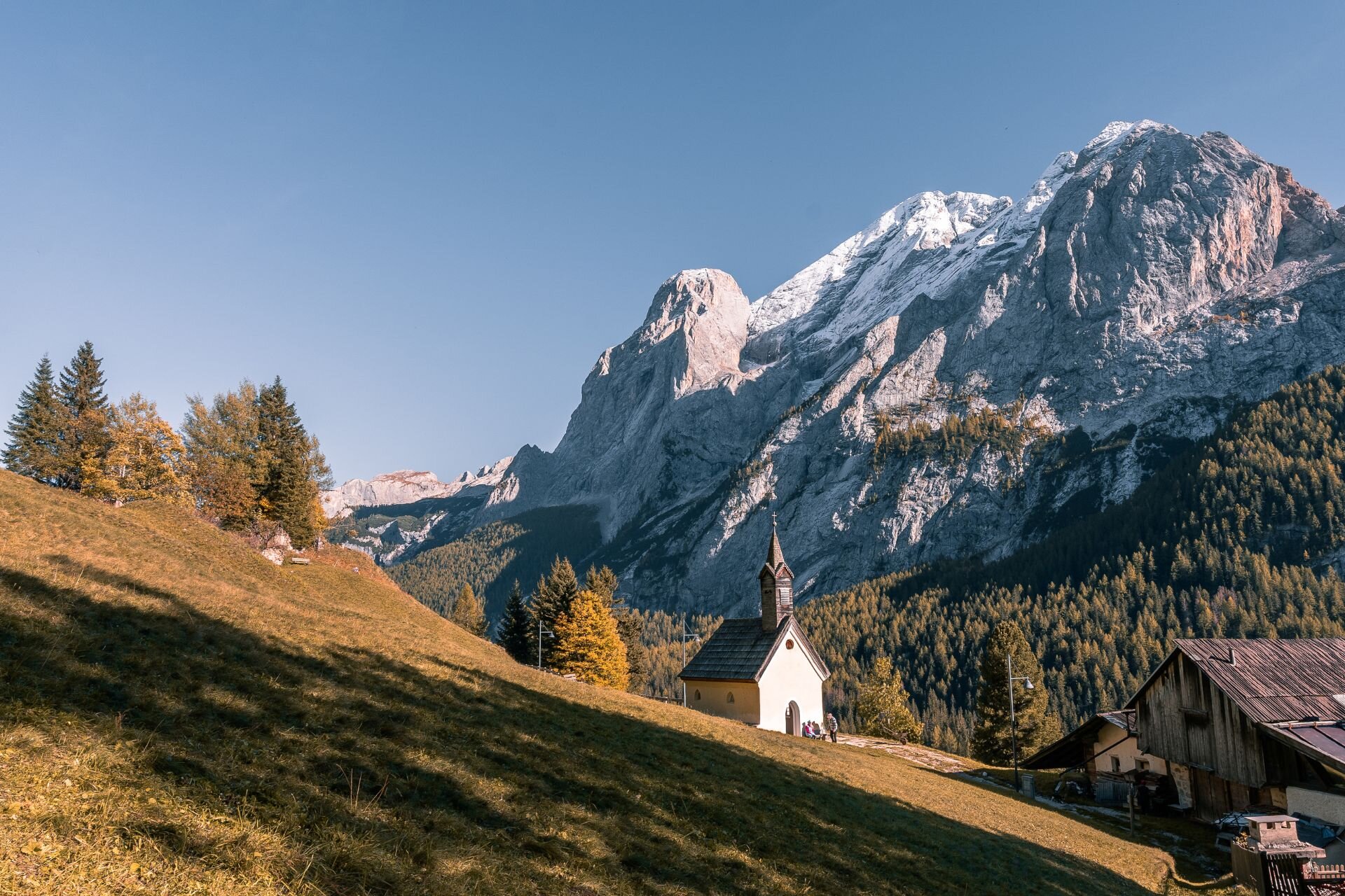 Chiesetta in mezzo al bosco autunnale con la Marmolada innevata sullo sfondo | © Archivio Immagini ApT Val di Fassa - Patricia Ramirez