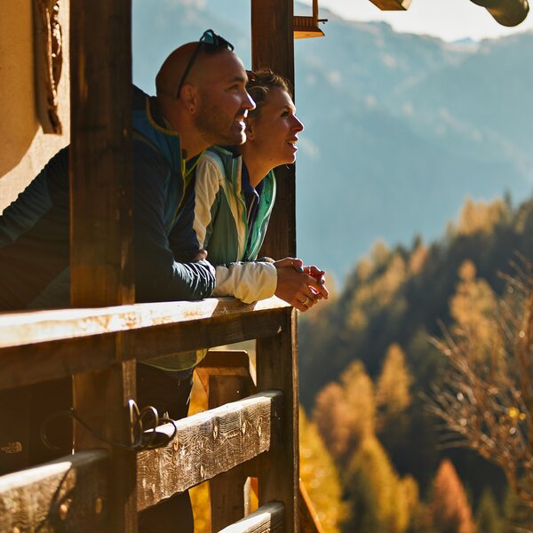 Persone che ammirano il paesaggio autunnale da un balcone in legno in Val di Fassa | © Fulvio Maiani Coolpixel - Archivio Immagini APT Val di Fassa